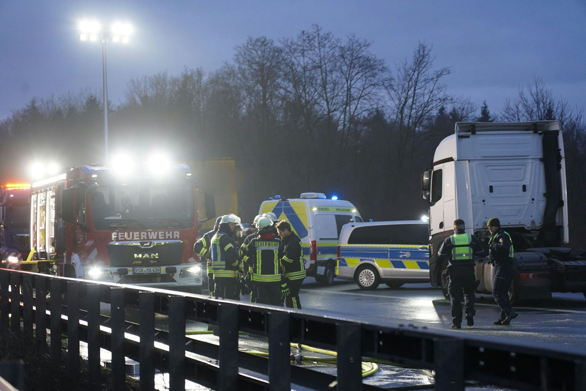 Feuerwehr und Polizei stehen auf der Fahrbahn nach einer durch Glätte ausgelösten Unfallserie mit mehreren Toten und vielen Verletzten auf der A44.