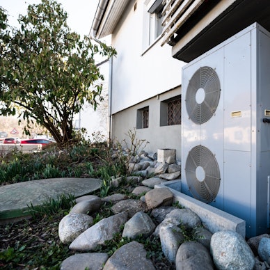 Das Foto zeigt die Lüftungsanlage einer Wärmepumpe vor einem Wohnhaus.