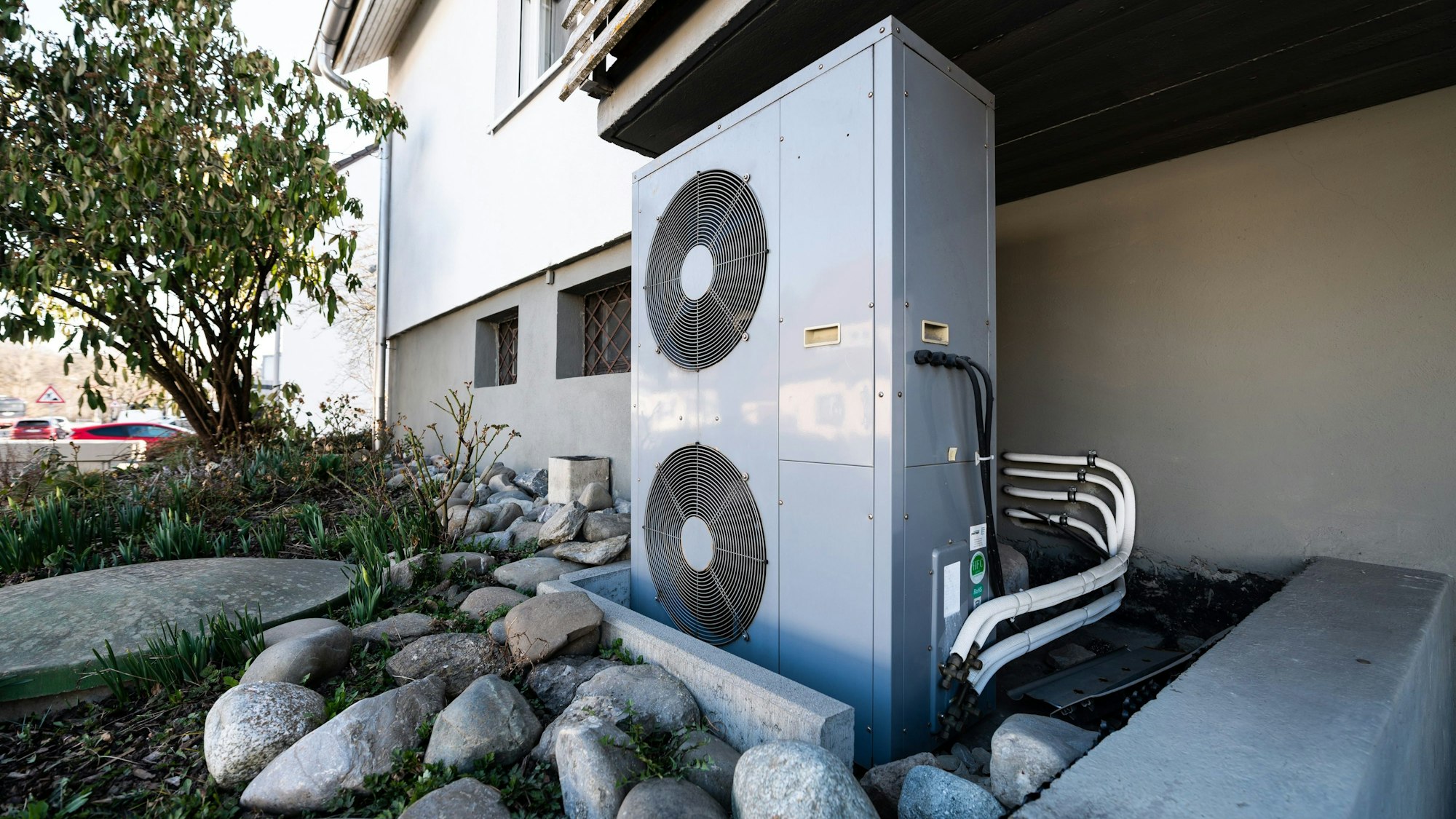 Das Foto zeigt die Lüftungsanlage einer Wärmepumpe vor einem Wohnhaus.