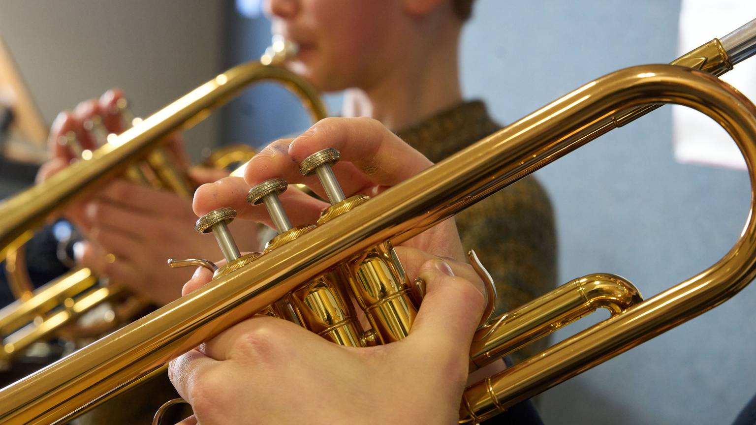 Zwei Jungen spielen im Unterricht einer Musikschule Trompete.