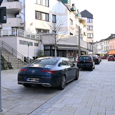 Rechts und links stehen Autos an der Straßenseite.