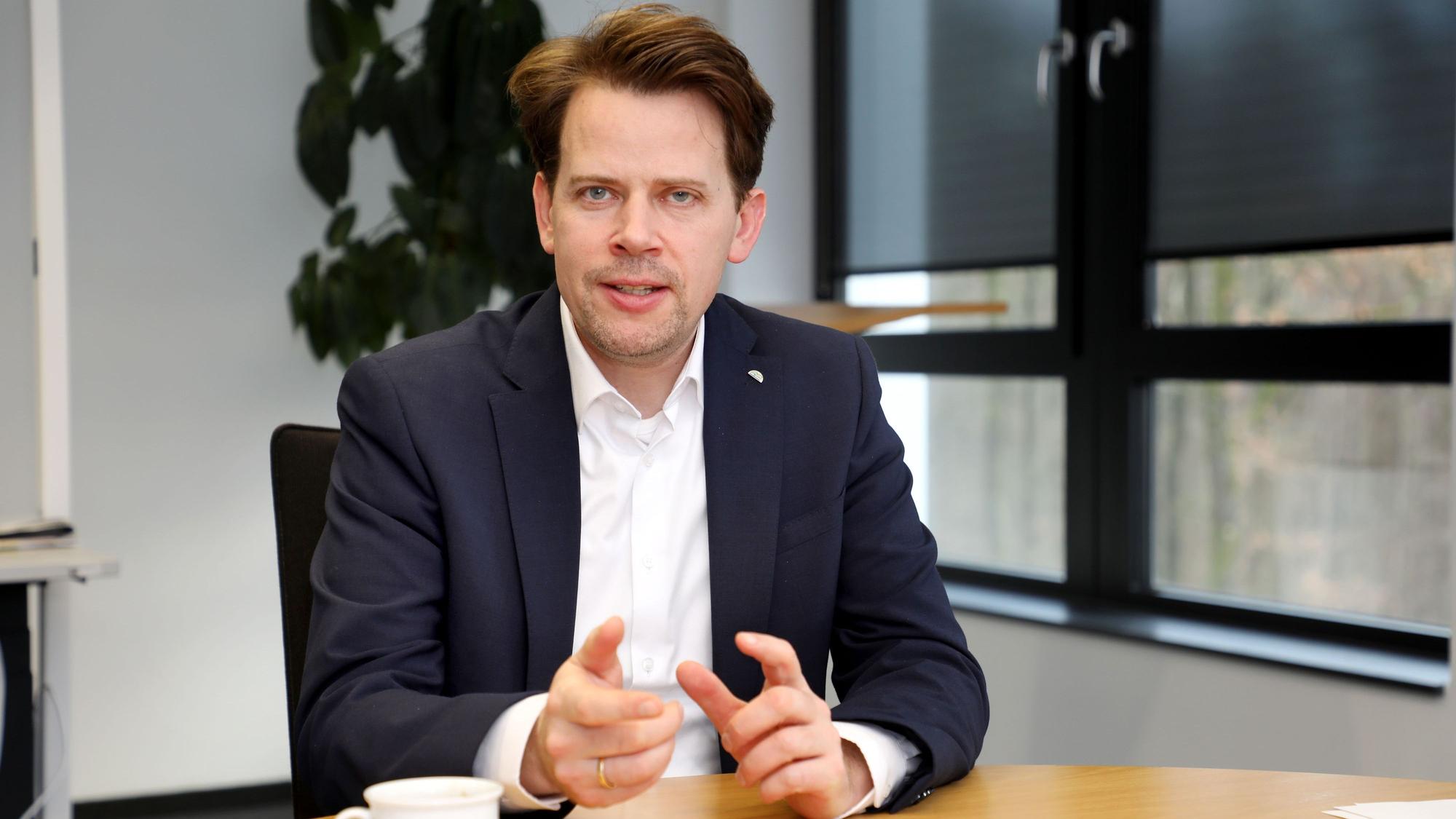 Landrat Arne von Boetticher sitzt in seinem Büro an einem Tisch.