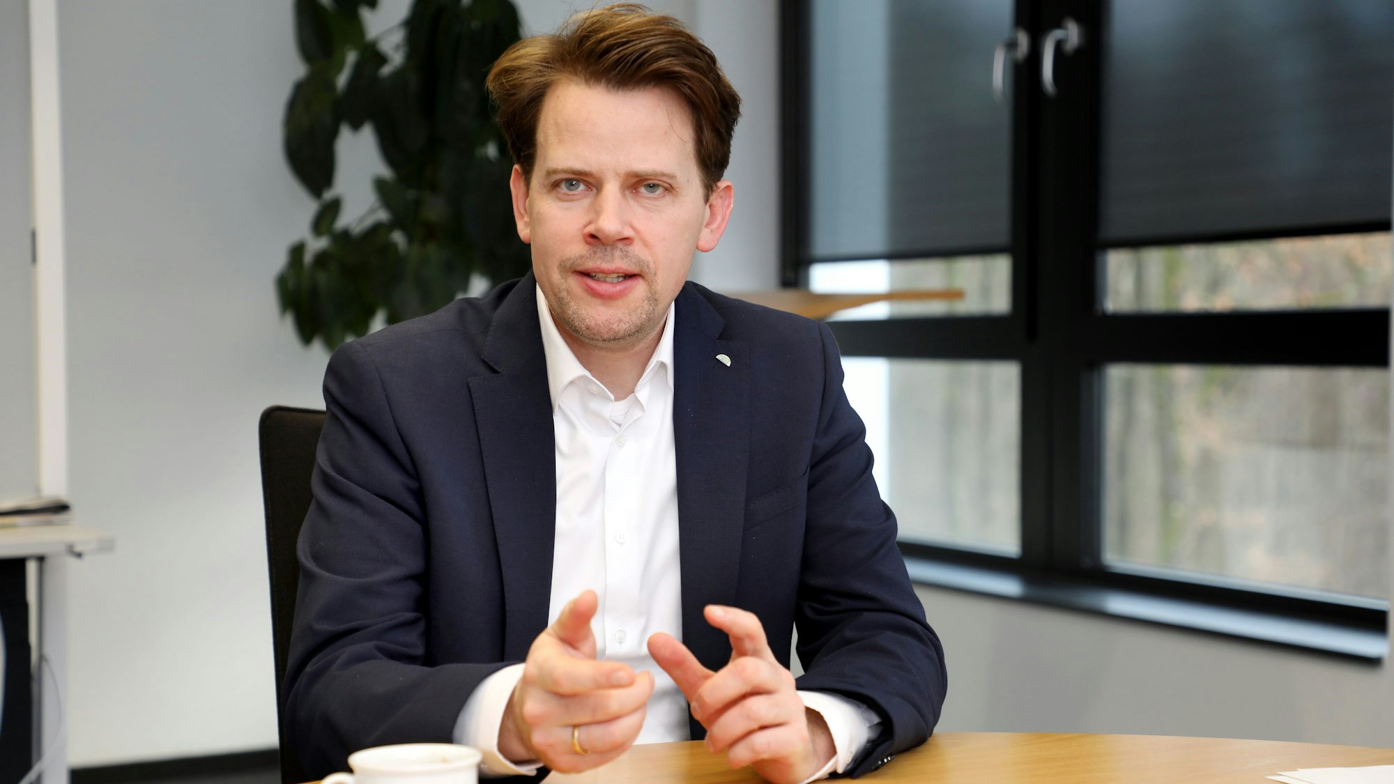 Landrat Arne von Boetticher sitzt in seinem Büro an einem Tisch.