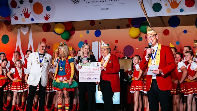 „Unger Uns“-Präsident Udo Beyers (rechts) dankt beim „Fastelovend der leiseren Töne“ für den Einsatz der Altenhilfe. Deren Vorsitzende Julia Heinen nimmt von Literatin Waltraut Piel einen symbolischen Scheck entgegen.