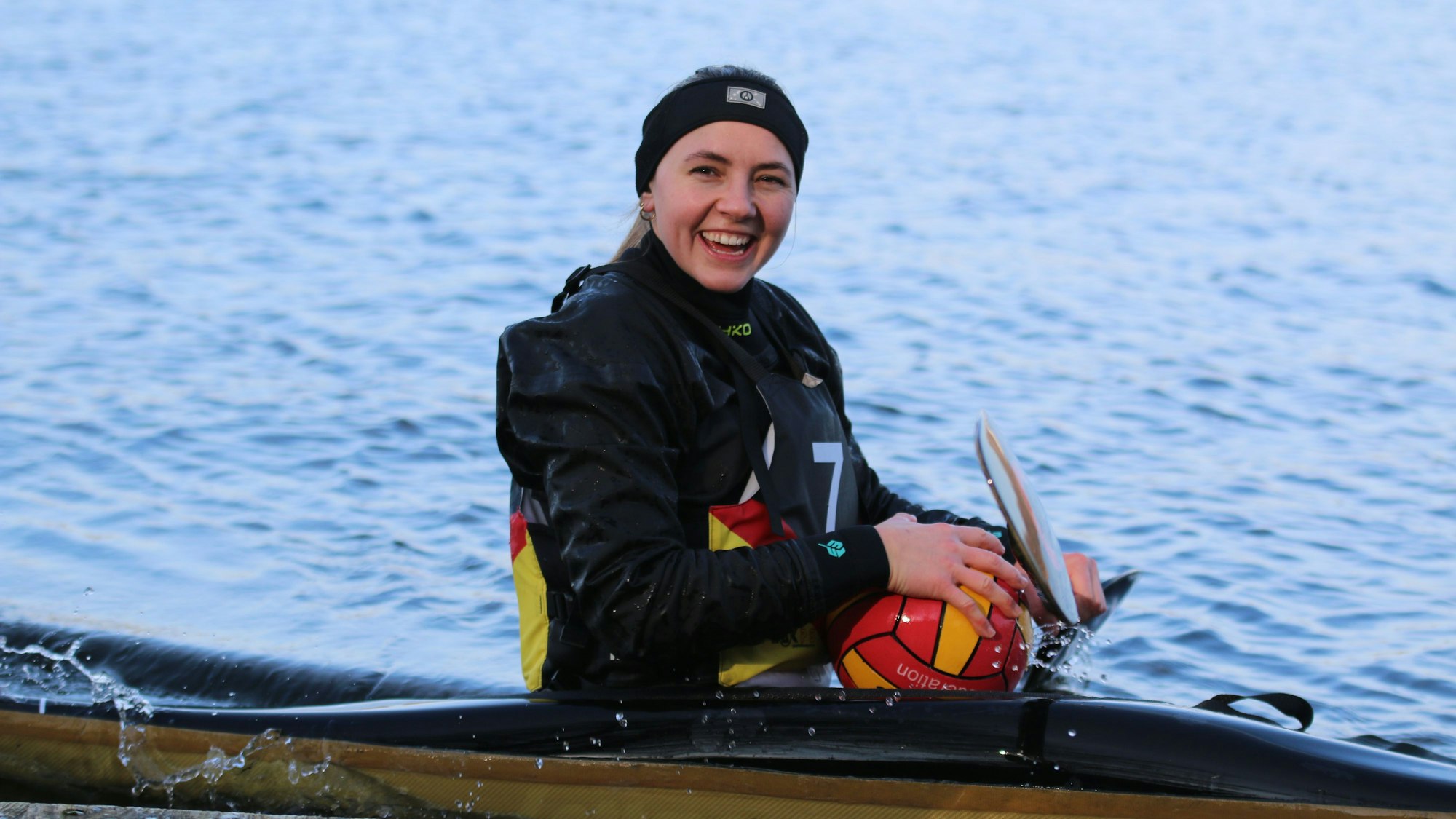 Leonie Wagner im Kajak auf dem Liblarer See, in der Hand hält sie Paddel und Ball.