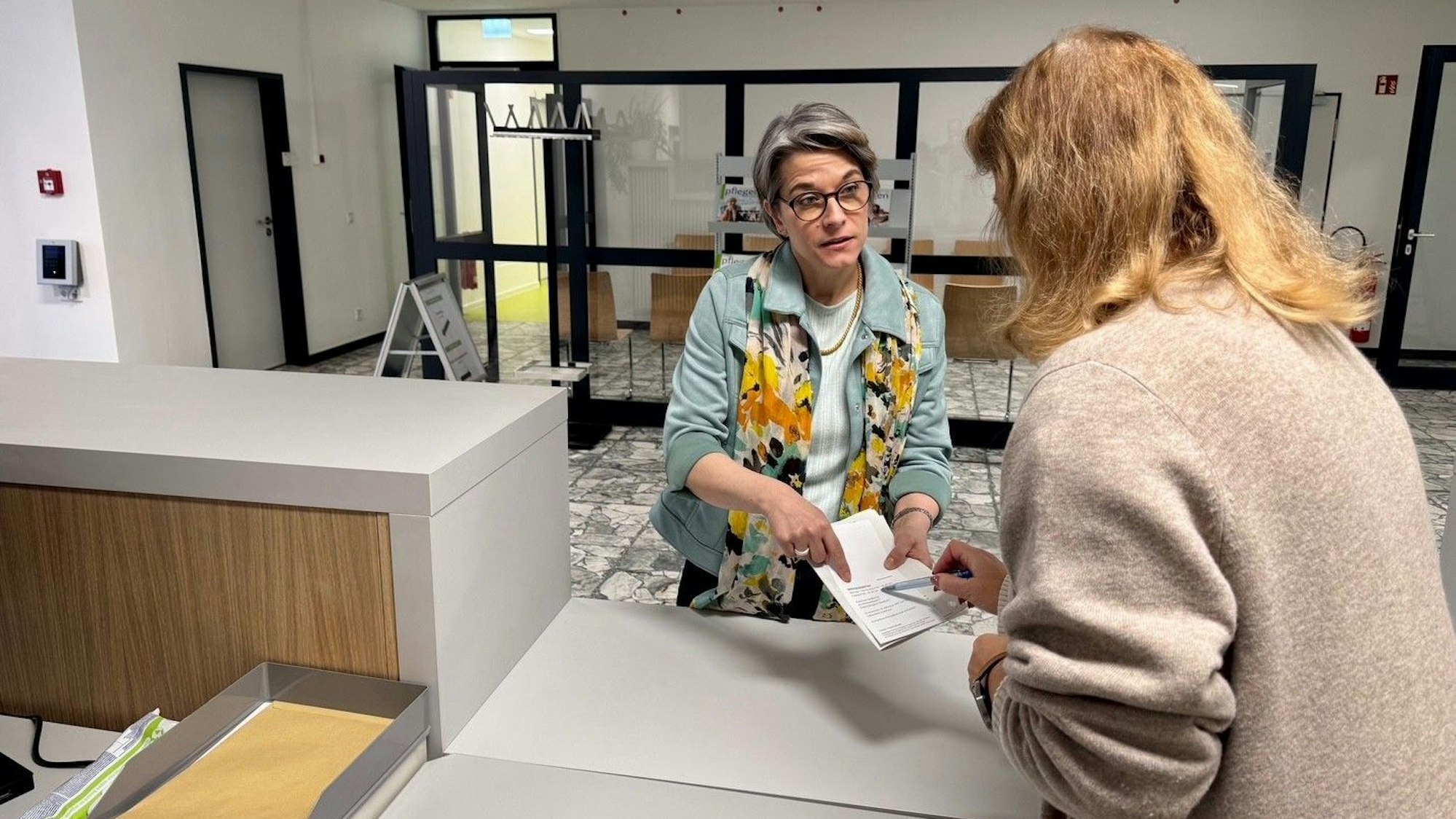 Am neuen Service-Point hilft eine Mitarbeiterin einer Dame in hellblauer Jacke.