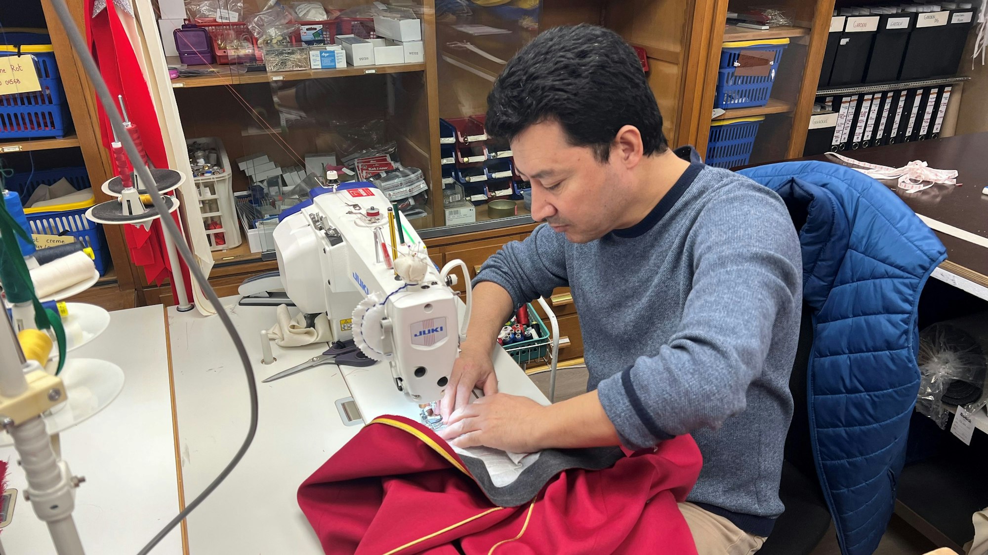 Ein Mitarbeiter der Uniformenschneiderei von „Brauchtum nach Maß“ arbeitet an der Nähmschine.