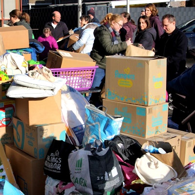 Kartons stapeln sich, dahinter stehen Menschen.