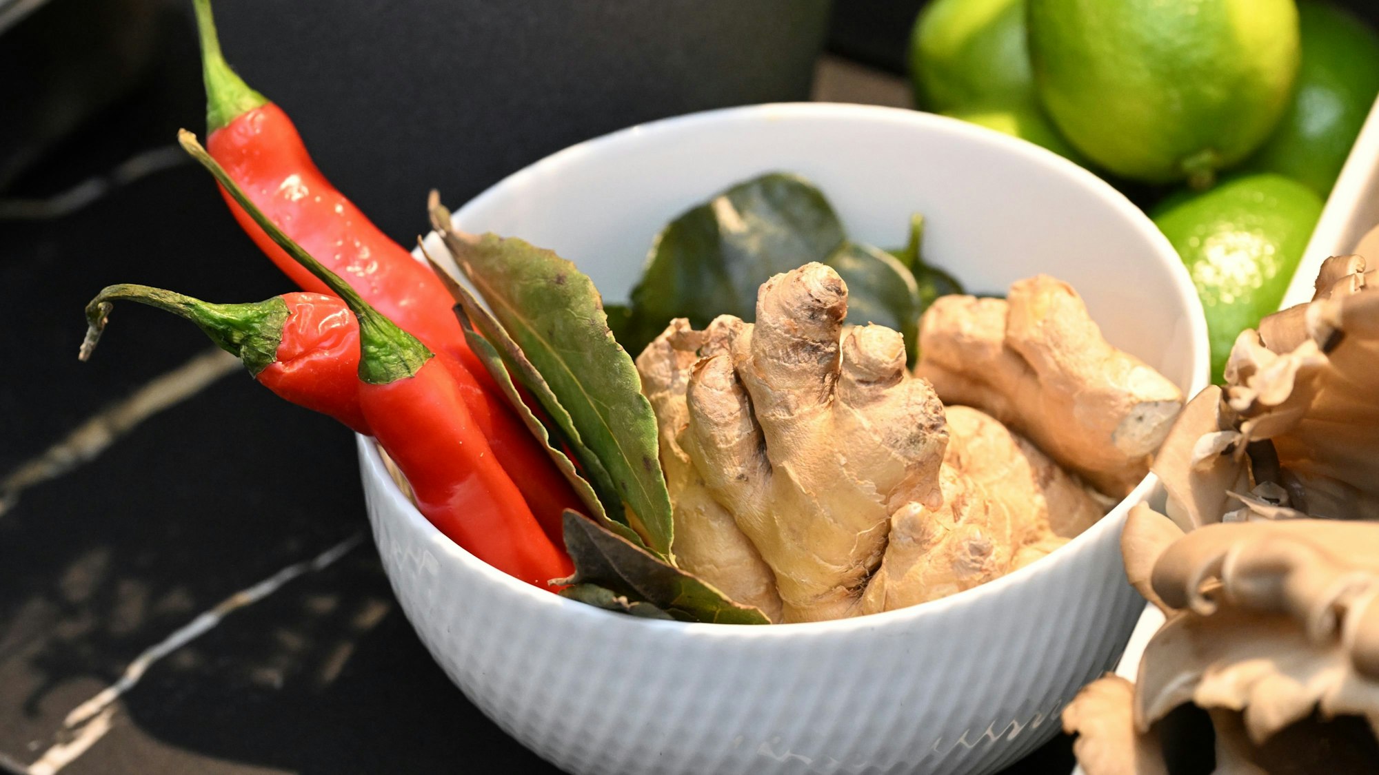 Ingwer, Peperoni und Gewürze liegen in einer weißen Schale.