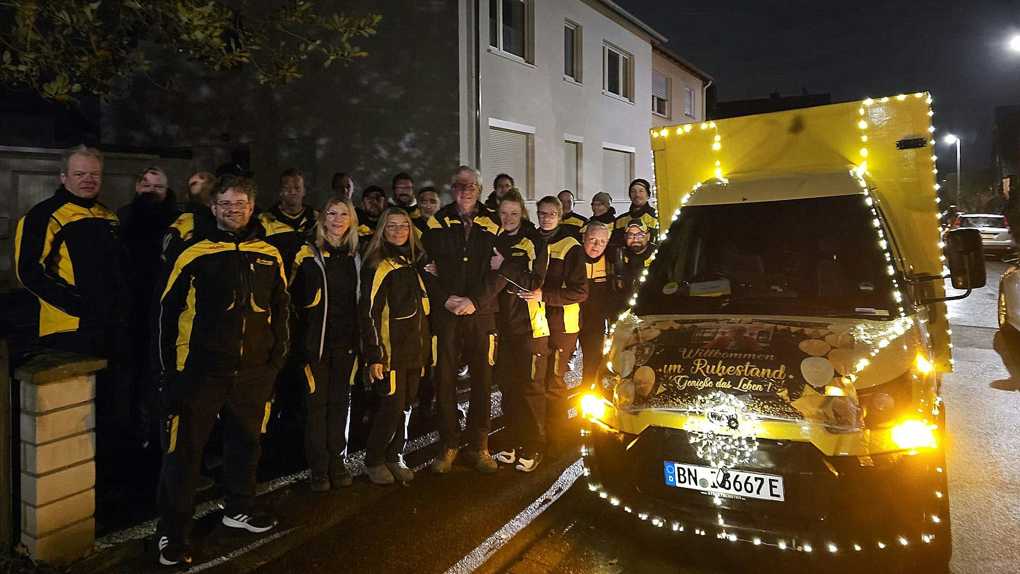 Eine Gruppe von Menschen steht neben einem mit einer Lichterkette geschmückten Transporter.