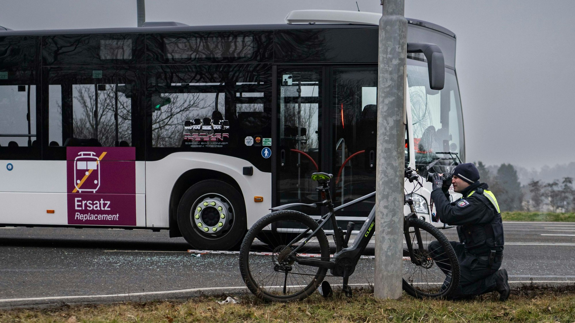 Das Bild zeigt einen Polizeibeamten, der ein Foto vom dem demolierten Pedelec macht. Im Hintergrund ist der Bus zu sehen.