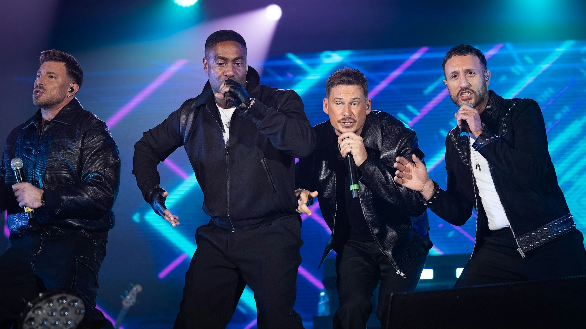 Blue performt 2024 auf einer Bühne in Italiean. Von links nach rechts: Duncan James, Simon Webbe, Lee Ryan and Antony Costa.