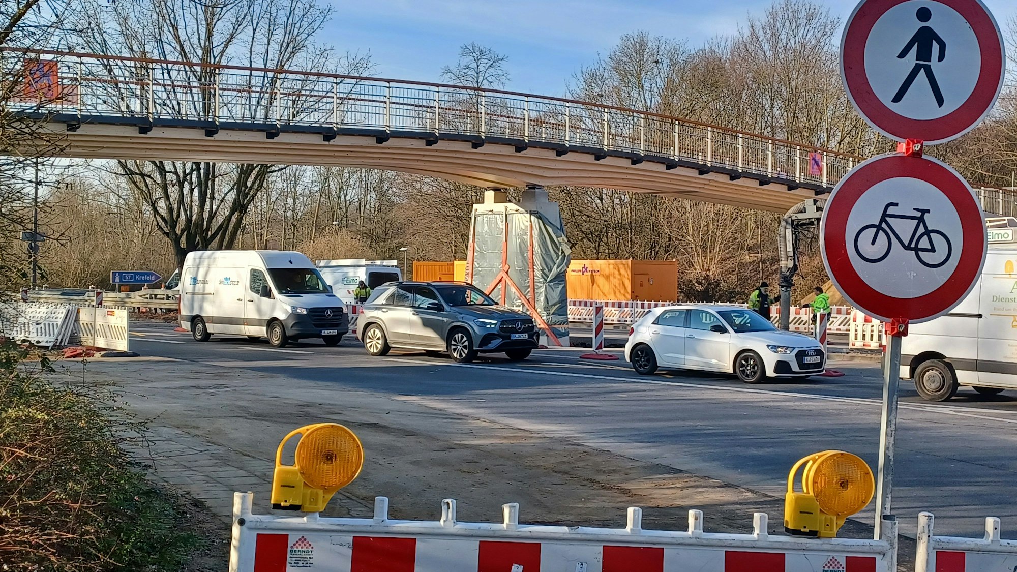 Eine nagelneue Rad- und Fußgängerbrücke aus Holz spannt sich über eine mehrspurige Straße.