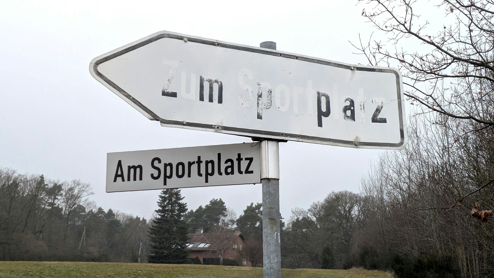 Hinweisschild mit kaum lesbarer Aufschrift „Zum Sportplatz“ in Satzvey.