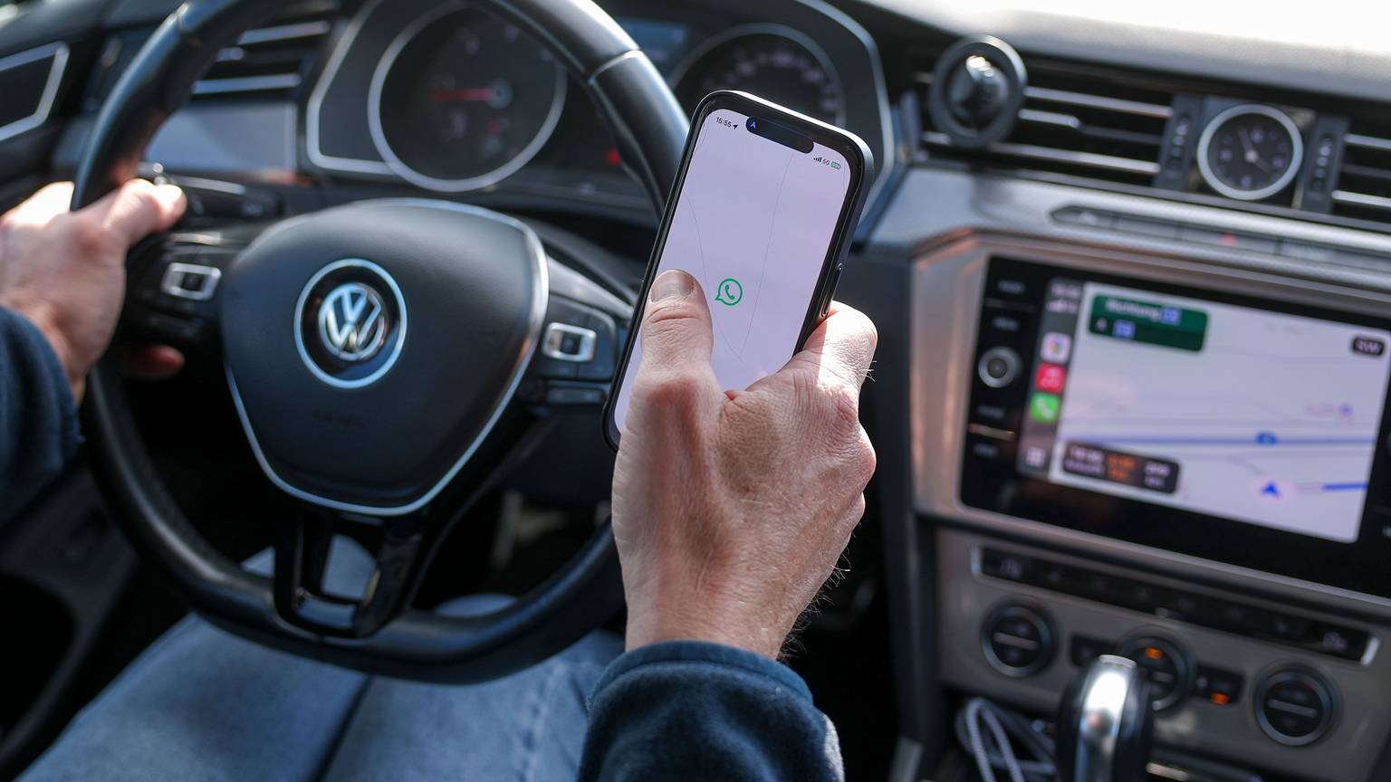 Ein Mann startet den WhatsApp Messenger auf einem Smartphone im Auto.