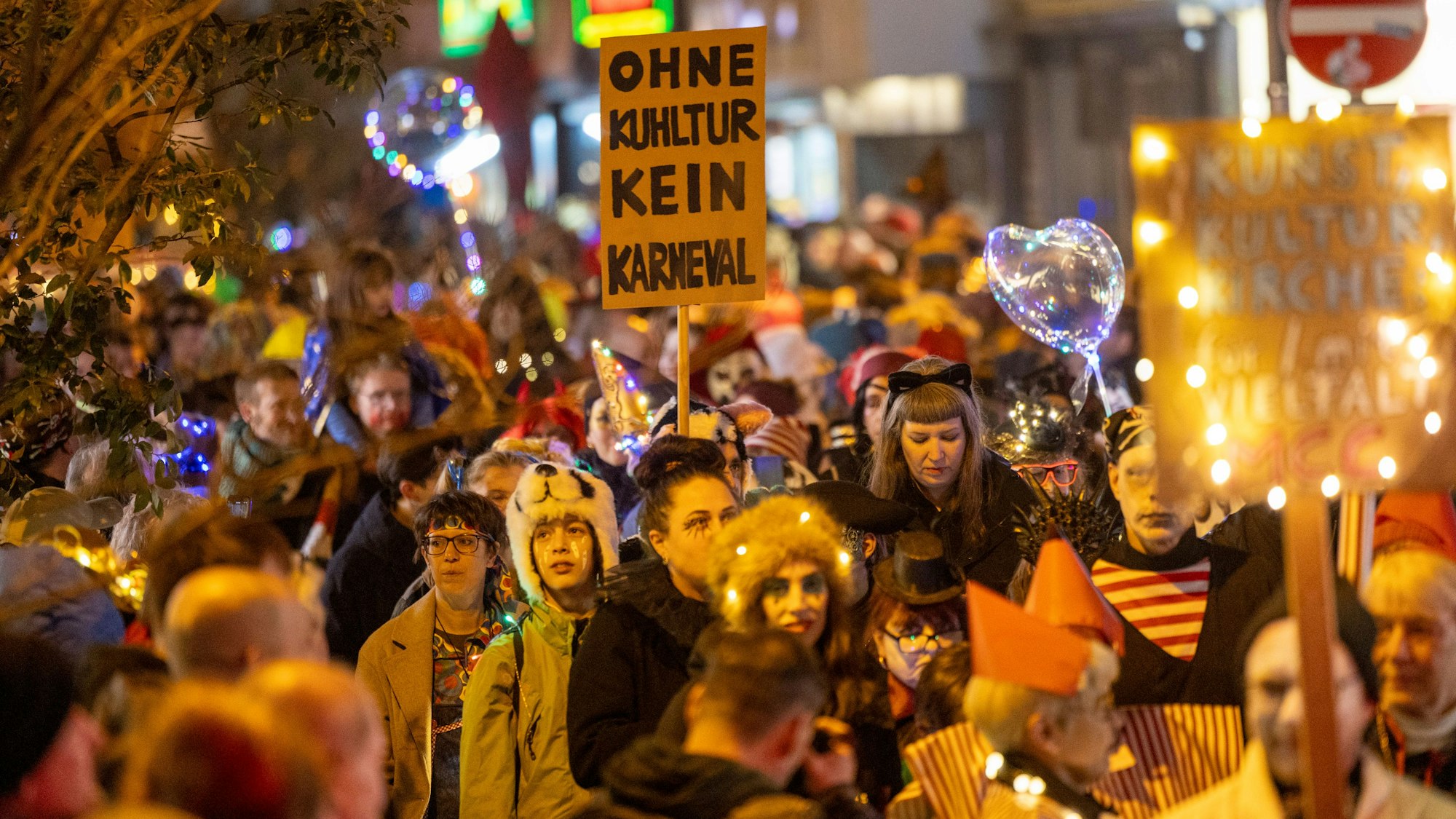 Der Geisterzug 2025. Die Menschen ziehen nachts kostümiert durch die Straße. Auf einem Demoschild steht „Ohne Kultur kein Karneval“.