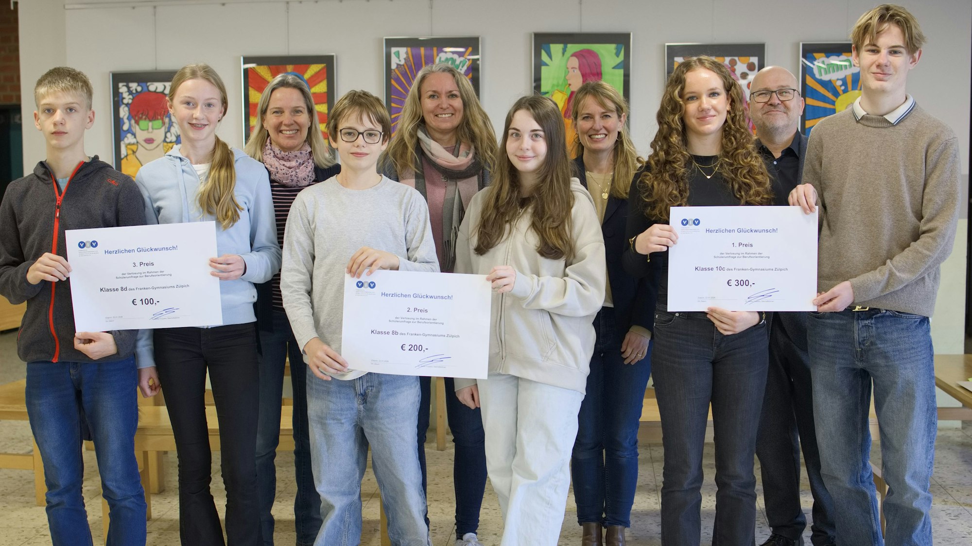 Einige Schüler aus Zülpich stehen zusammen und halten drei symbolische Schecks in den Händen, die sie erhalten haben.