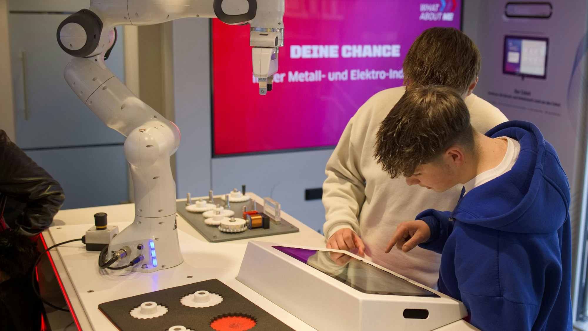 Im Infotruck des Arbeitgeberverbands Gesamtmetall stehen zwei Schüler an einem Roboter, den sie selbst steuern.