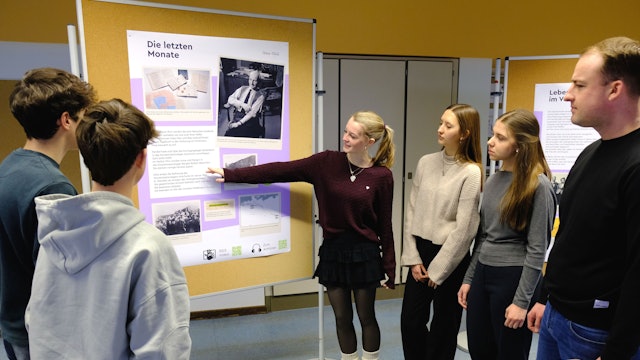 Fünf Schülerinnen und Schüler sowie ein Lehrer der Clara-Fey-Schule in Schleiden stehen zusammen und betrachten ein Plakat an einer Stellwand.