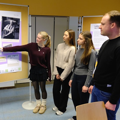 Fünf Schülerinnen und Schüler sowie ein Lehrer der Clara-Fey-Schule in Schleiden stehen zusammen und betrachten ein Plakat an einer Stellwand.