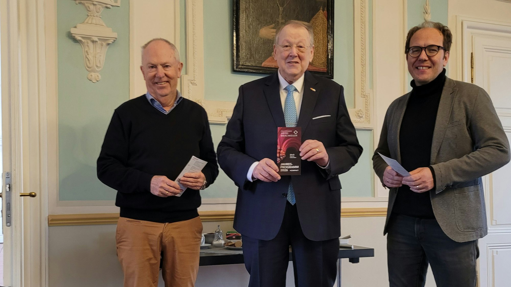 Drei Männer lächeln in die Kamera.