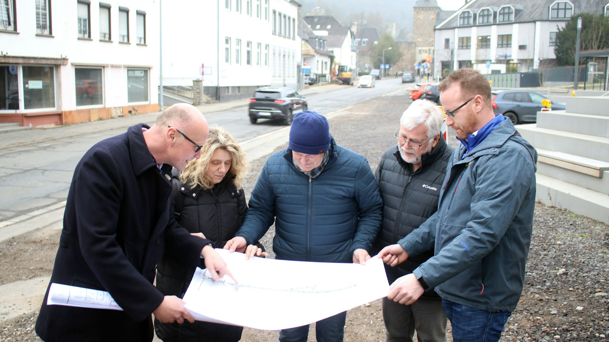 Vier Männer und eine Frau schauen auf Planungsunterlagen.