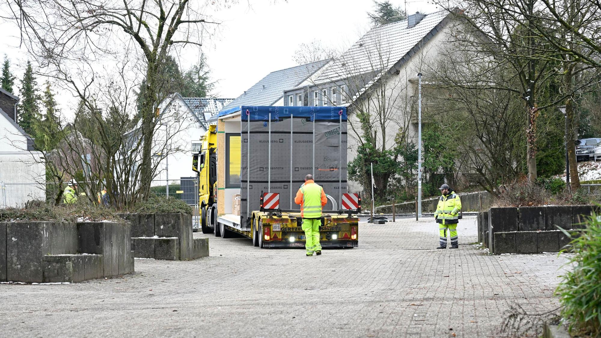 Neben und hinter dem Transporter her gehen Bauarbeiter.