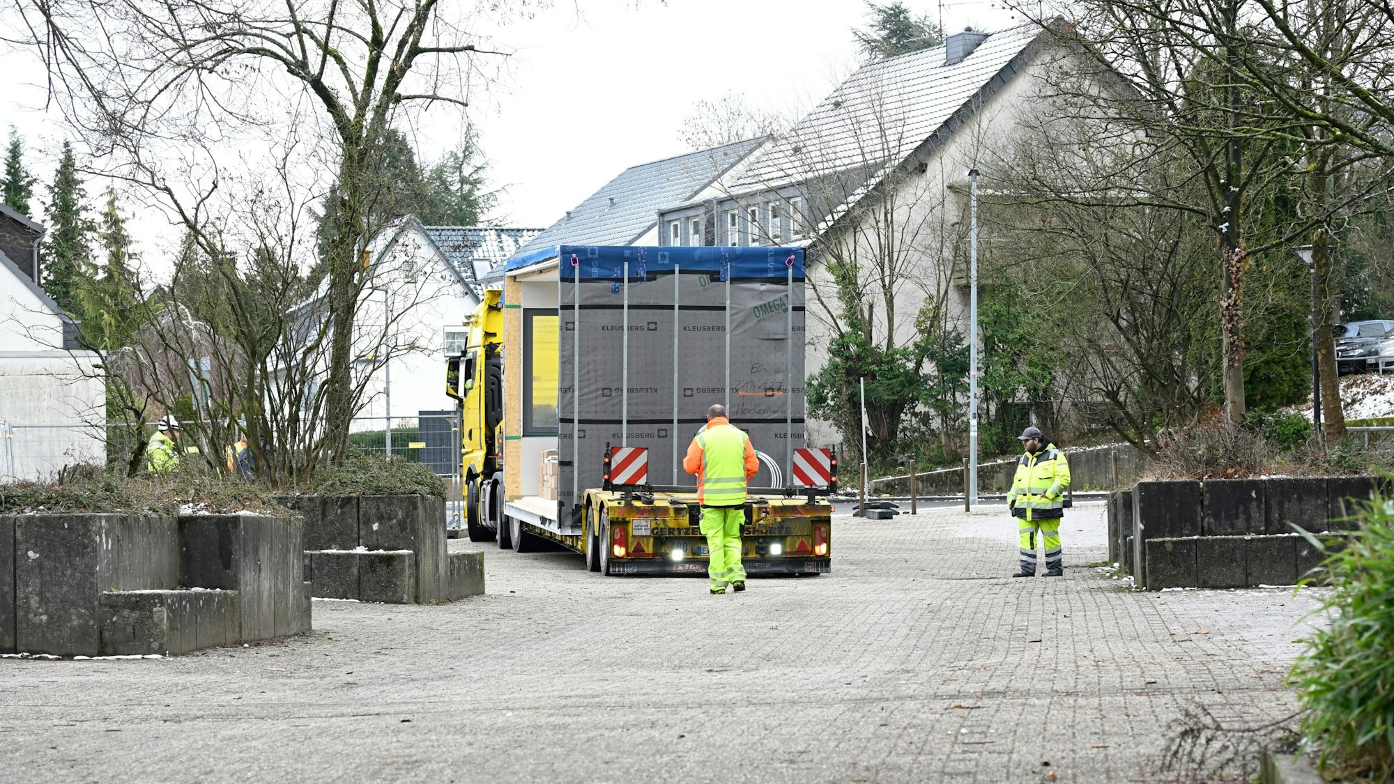 Neben und hinter dem Transporter her gehen Bauarbeiter.
