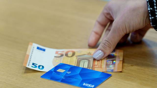 Eine Bezahlkarte für Asylbewerberinnen und Asylbewerber und ein 50 Euro Schein liegen nebeneinander.