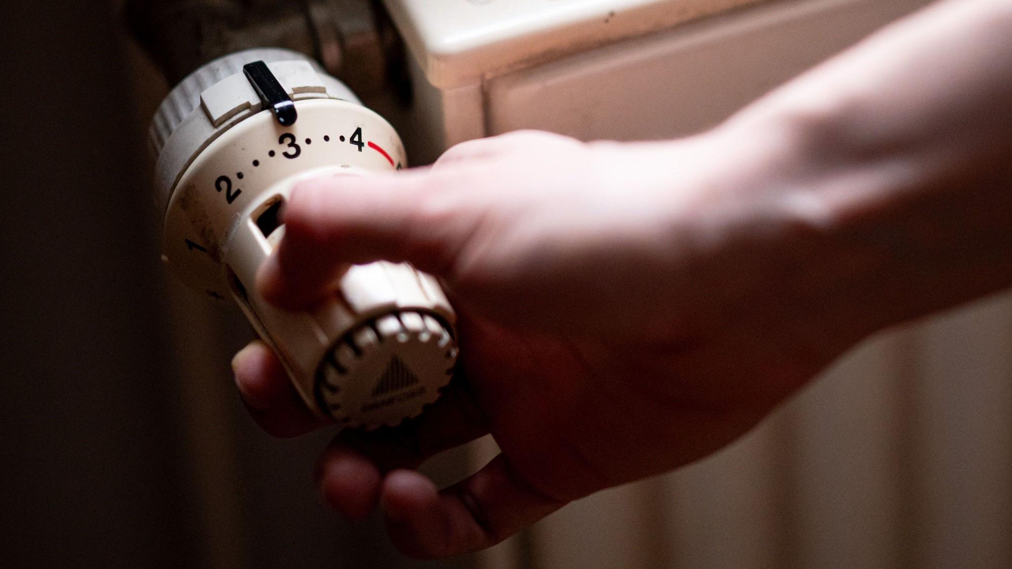 Eine Person benutzt einen Heizkörper in einer Altbauwohnung.
