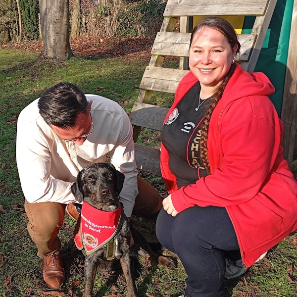Das Foto zeigt zwei Menschen mit einem Hund.
