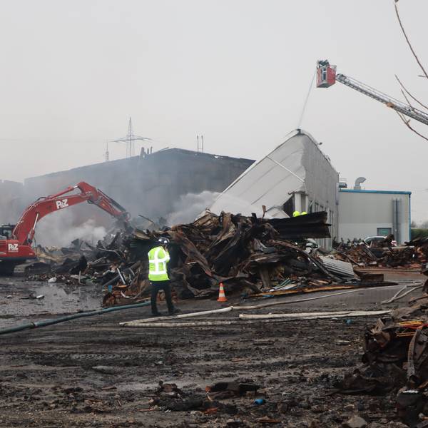 Noch war das Feuer am Mittwochmorgen nicht gänzlich gelöscht. Ein Bagger zieht Schutt auseinander, damit die Feuerwehrleute zu Glutnestern vordringen kann.
