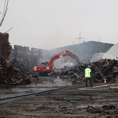 Noch war das Feuer am Mittwochmorgen nicht gänzlich gelöscht. Ein Bagger zieht Schutt auseinander, damit die Feuerwehrleute zu Glutnestern vordringen kann.