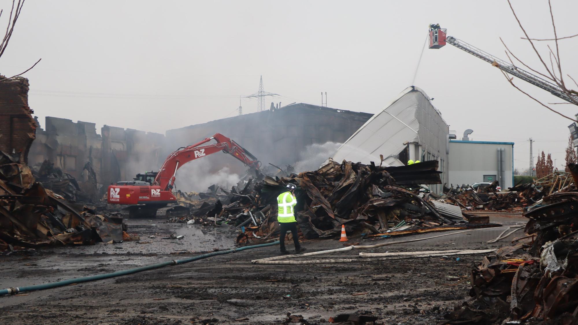 Noch war das Feuer am Mittwochmorgen nicht gänzlich gelöscht. Ein Bagger zieht Schutt auseinander, damit die Feuerwehrleute zu Glutnestern vordringen kann.