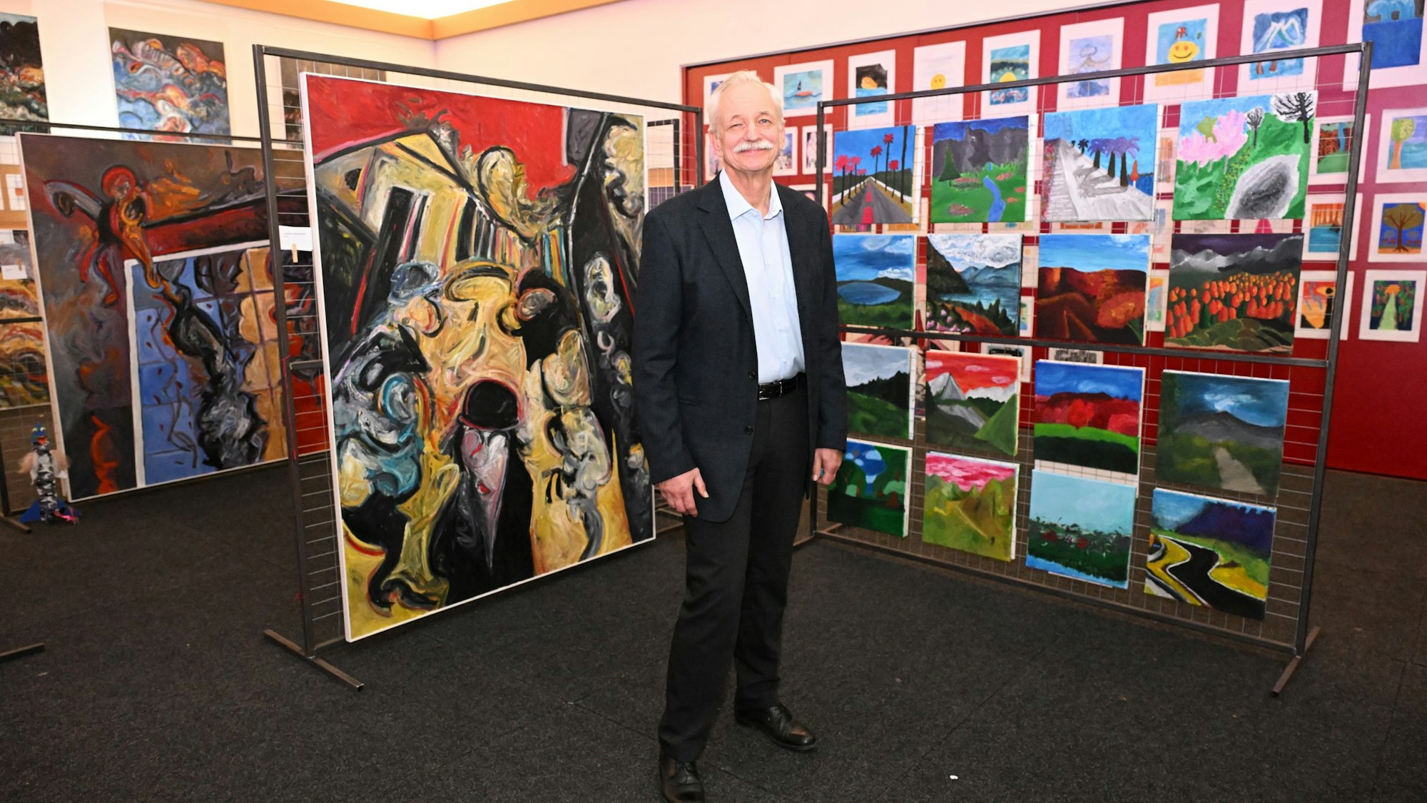 Der Schulleiter steht vor einem Gemälde.