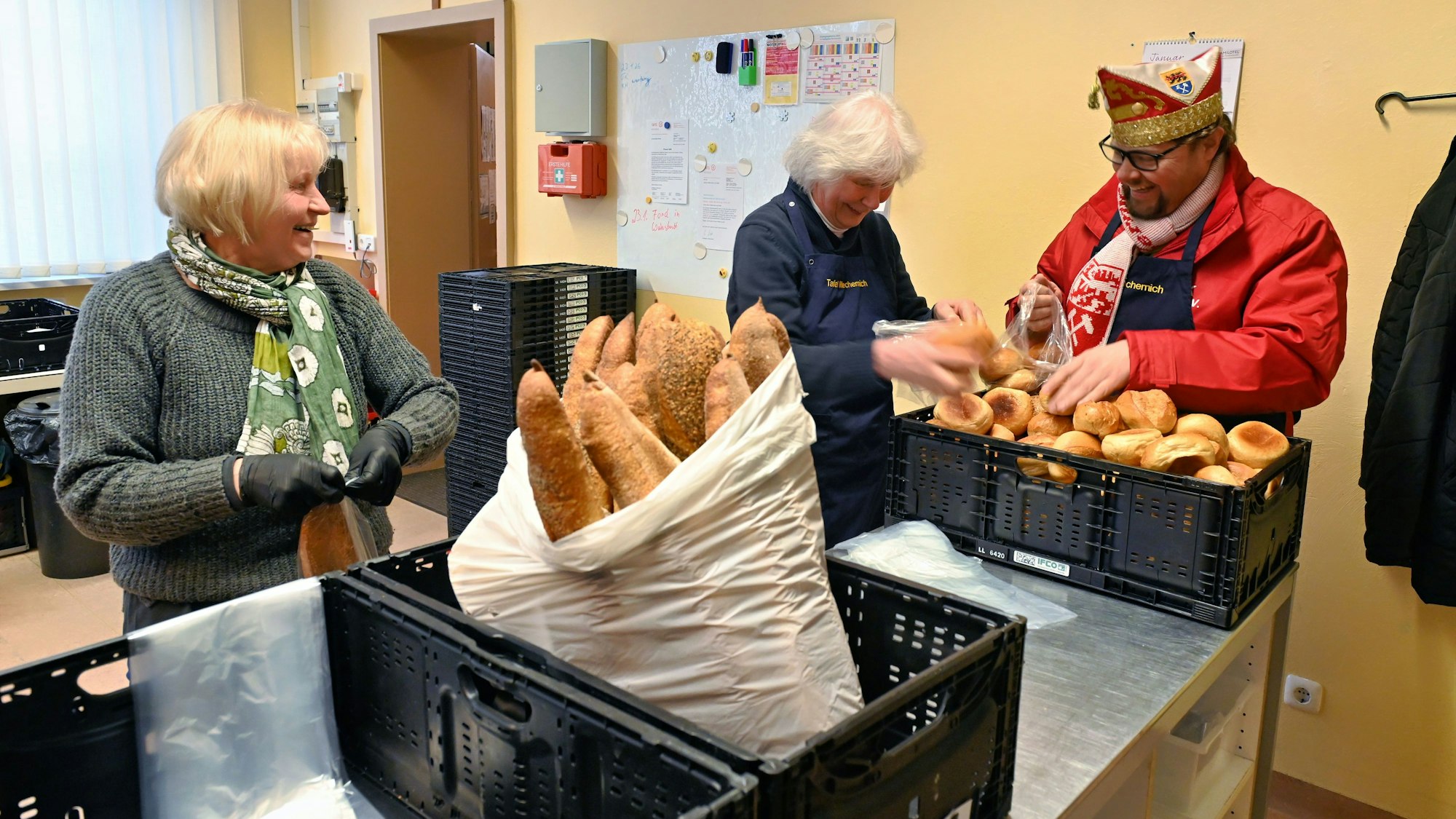 Torsten Krieg packt neben zwei älteren Damen Brötchen aus einem Korb in eine Plastiktüte.