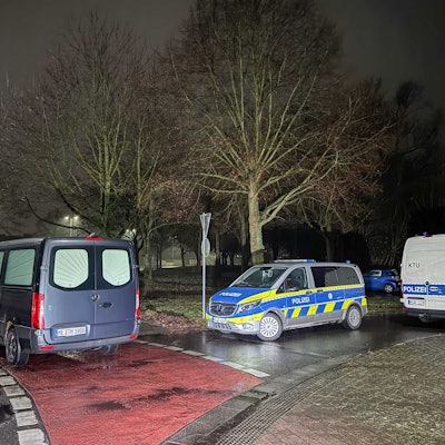 Das Bild zeigt Polizeiwagen an dem Fundort einer Leiche in Dormagen. Foto: Vincent Kempf/dpa