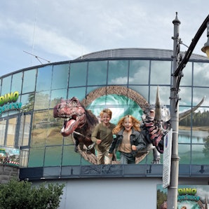 Große Darstellungen von Kindern und Dinosauriern an der Glasfassade eines Gebäudes.