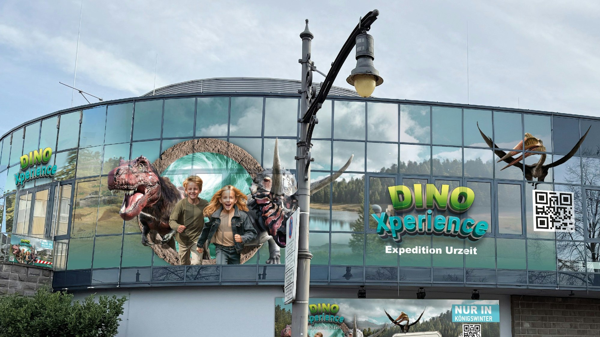 Entwürfe auf den Scheiben eines Gebäudes zeigen im Großformat zwei Kinder sowie Dinosaurierdarstellungen.