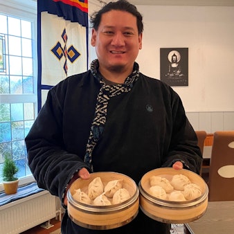 Zu sehen ist Gastronom Suolangzelan, der tibetische Teigtaschen in seinen Händen hält.