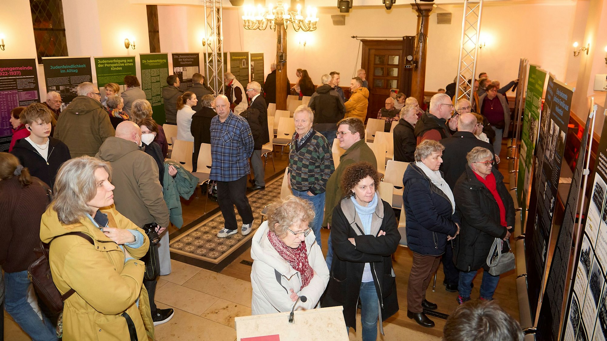 Das Bild zeigt zahlreiche Menschen, die sich die Ausstellung anschauen.