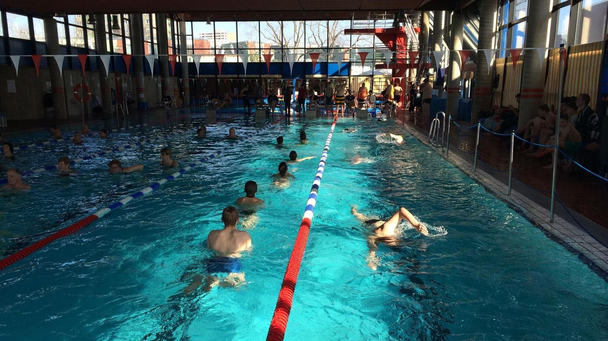 Auf dem Foto sind Badegäste im Becken eines Hallenbades zu sehen.