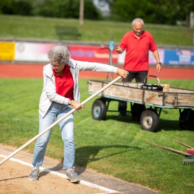 Bei einem Leichtathletik-Wettkampf helfen ein Mann (im Hintergrund) und eine Frau bei der Organisation.