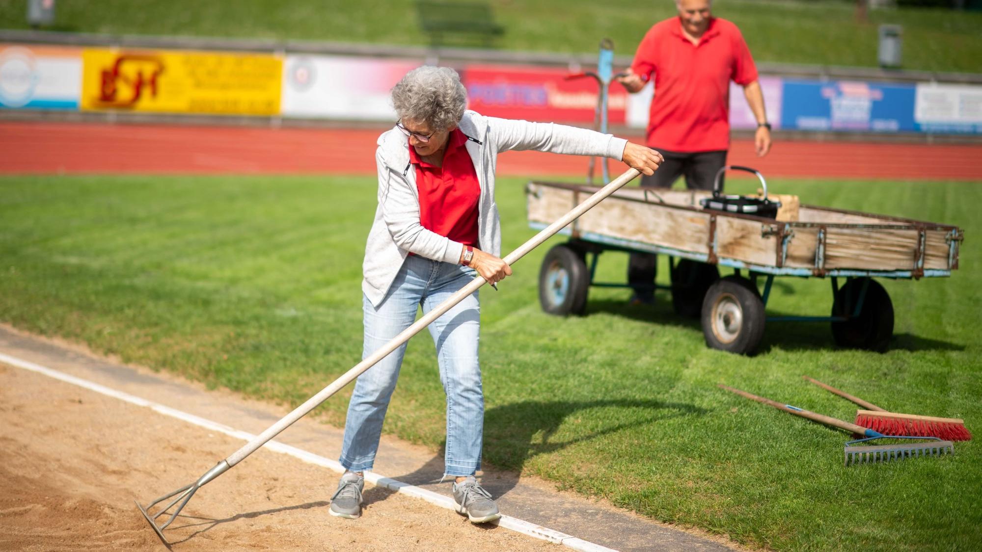 Bei einem Leichtathletik-Wettkampf helfen ein Mann (im Hintergrund) und eine Frau bei der Organisation.