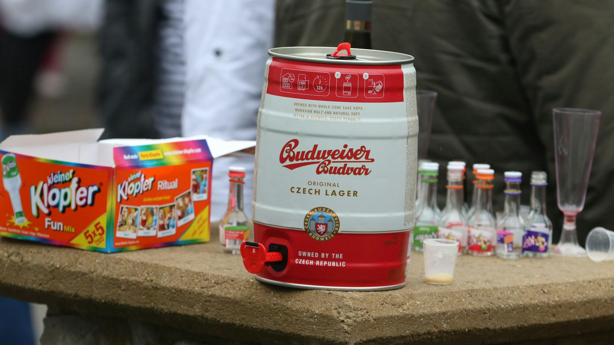 Eine Fünf-Liter-Dose Bier sowie Fläschchen voller alkoholischer Getränke stehen bei einem Karnevalszug auf einem Tisch.