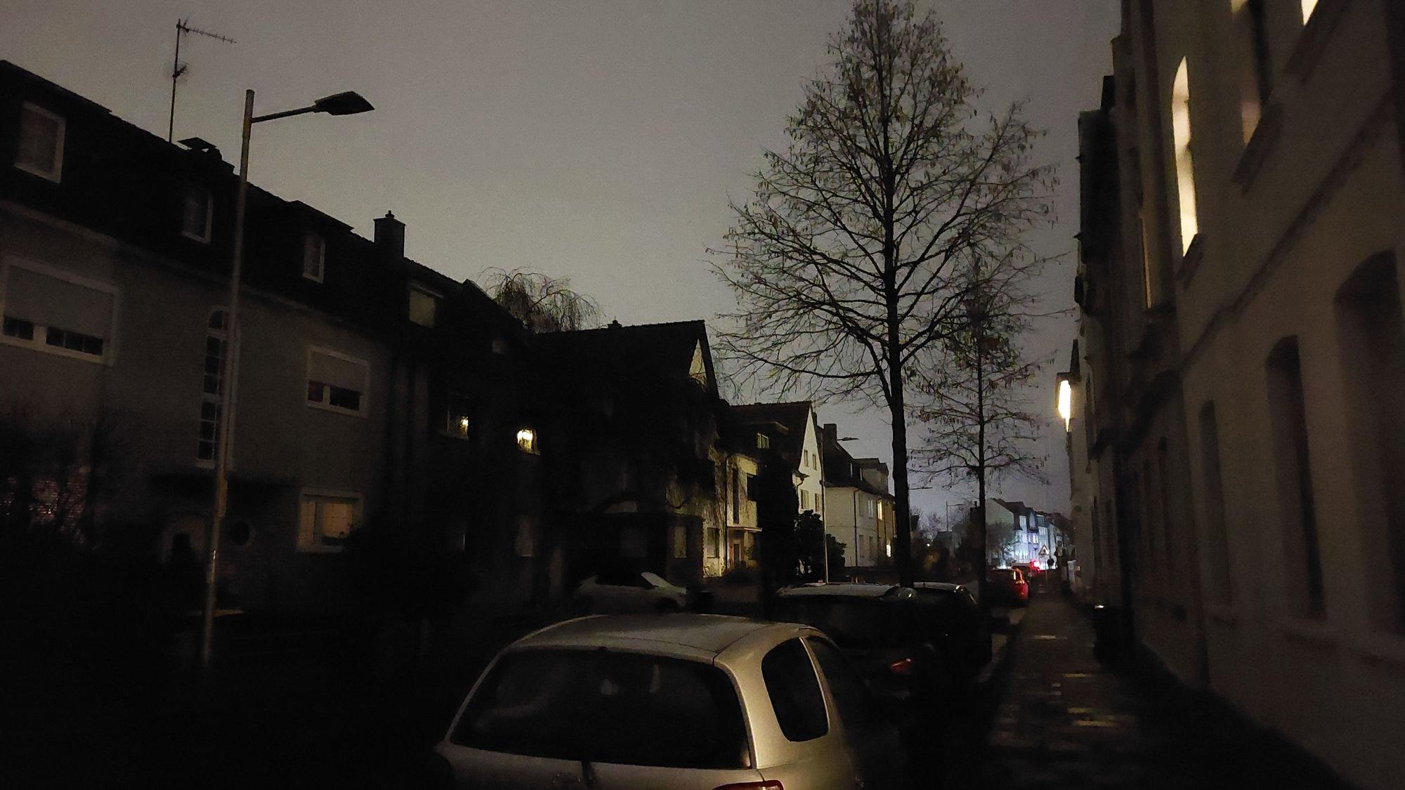 Eine dunkle Straße in einem Wohnviertel. Die Laternen sind nicht im Betrieb.