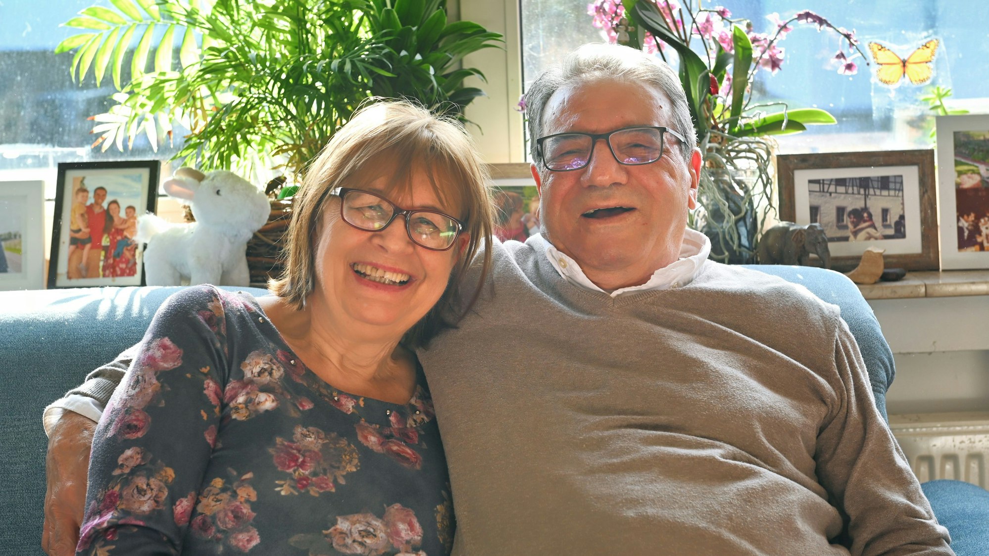 Ingrid und Saleem Alhasan sitzen im heimischen Wohnzimmer auf dem Sofa, er hat den Arm um seine Frau gelegt.