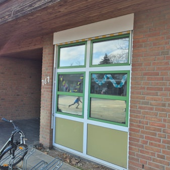 Das Bild zeigt den Eingang zur Kita. Vorne parkt ein Fahrrad an einem Ständer.