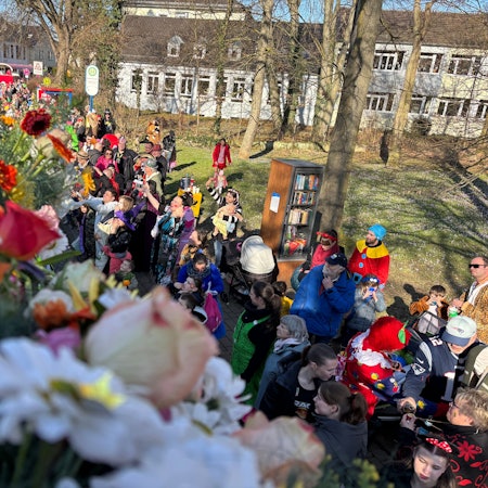 Der Karnevalszug geht durch Troisdorf. Am Straßenrand stehen verkleidete Menschen.