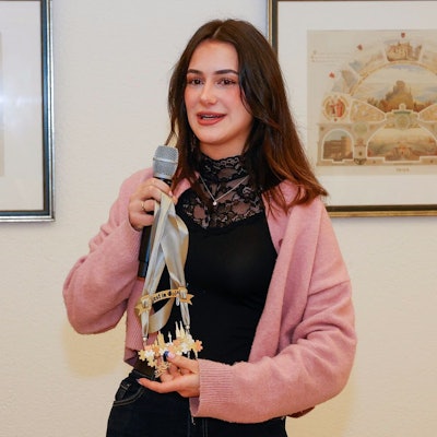 Hannah Homberg hält ein Mikrofon und ihren Orden in der Hand.